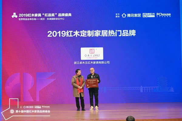 红星美凯龙集团高级顾问吴为为（左）为“2019红木定制家居热门品牌”获奖企业——卓木王颁奖